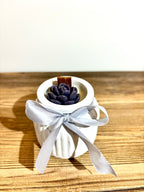 Vidutinė žvakė indelyje su kaspinėliu